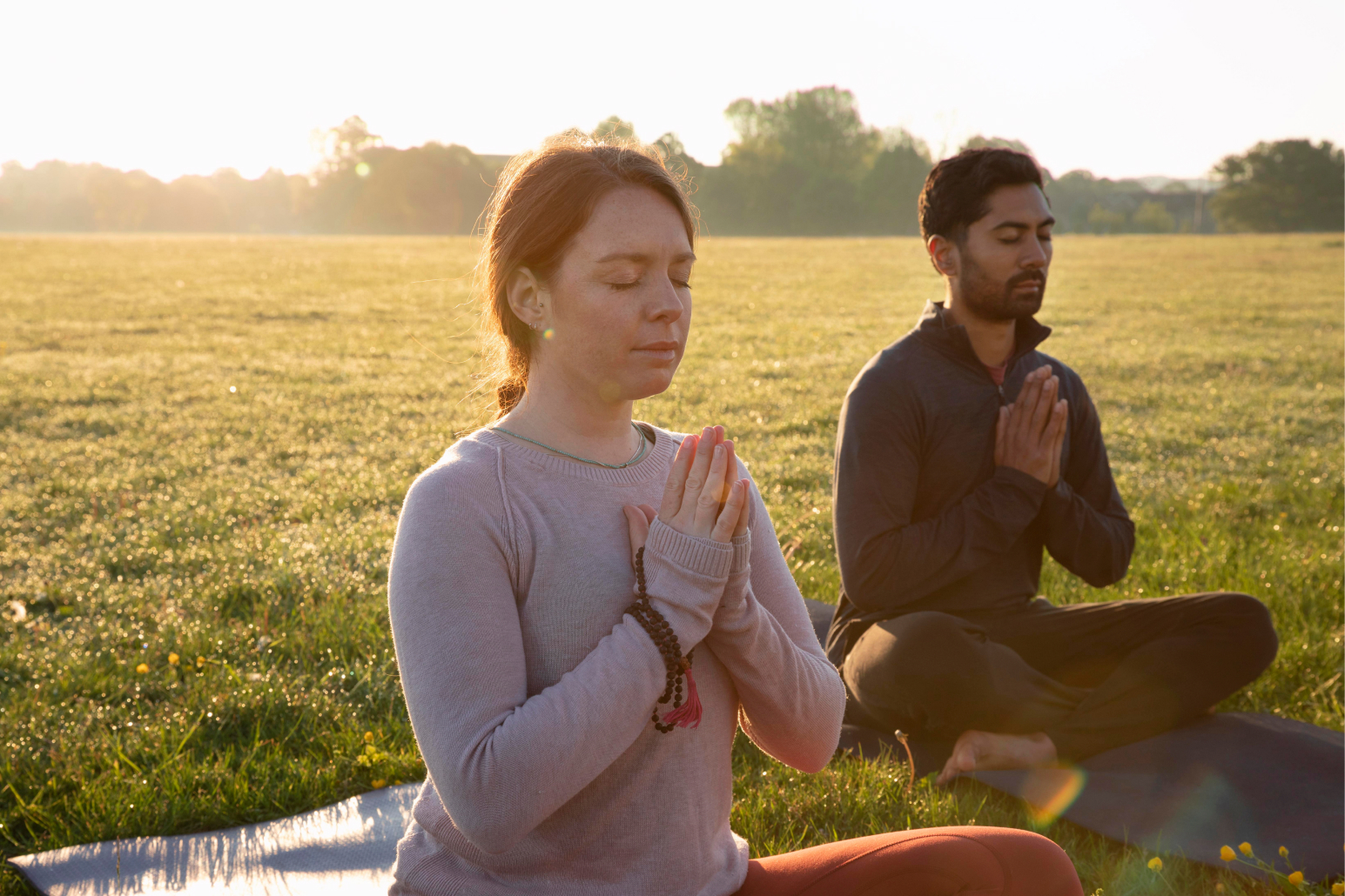 Pareja meditando al aire libre en un campo abierto